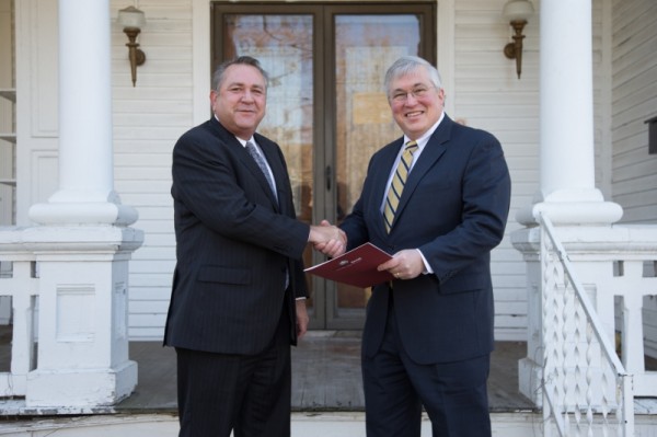 Heritage Bank President Keith Bennett (left) shakes hands with APSU President Tim Hall on Dec. 11 after presenting the deed to the house behind them, located at 1220 Madison St. APSU plans to sell the property, with the proceeds going toward the Governors Stadium renovation project. (Photo by Beth Liggett, APSU photographer)